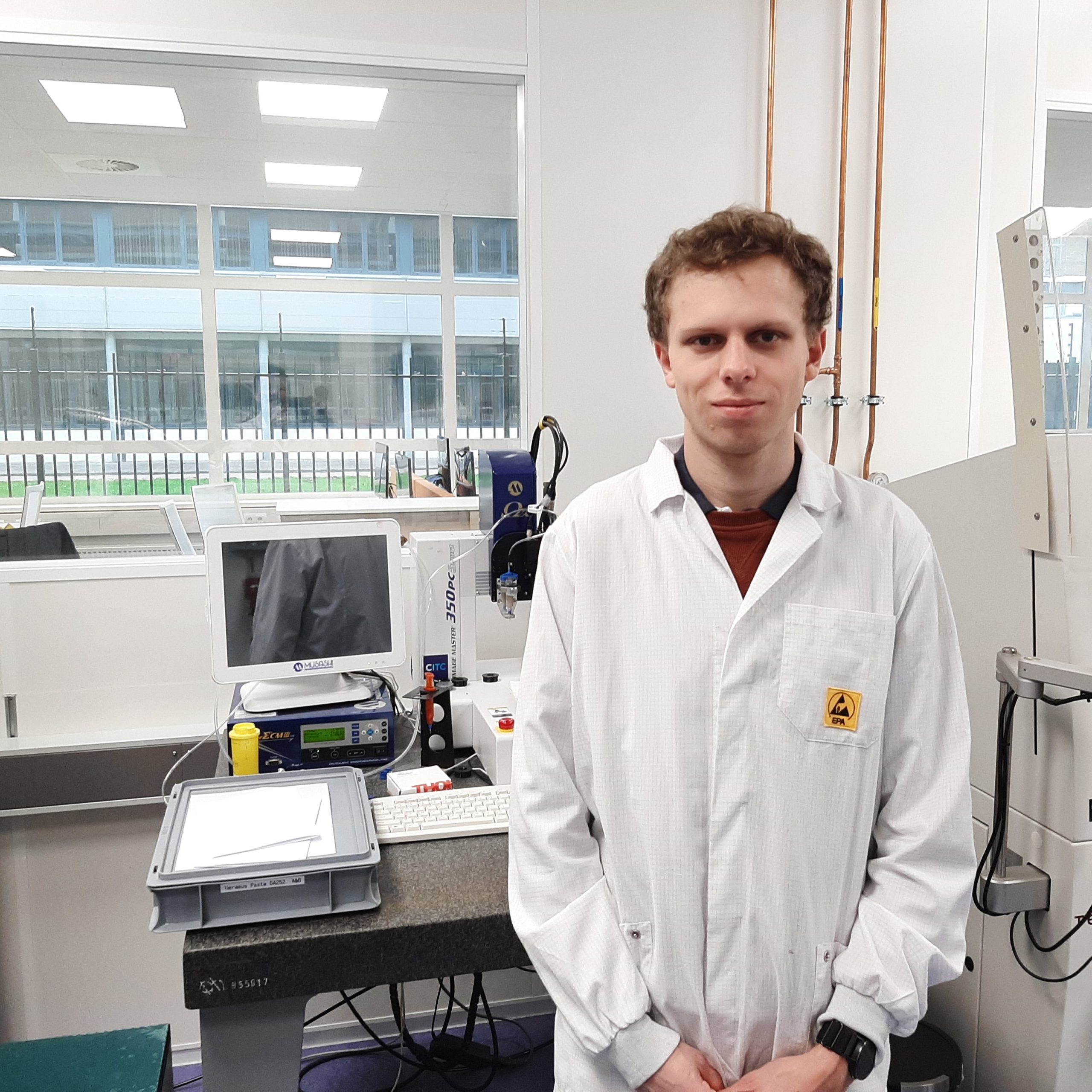 Young man standing in front of machine in lab